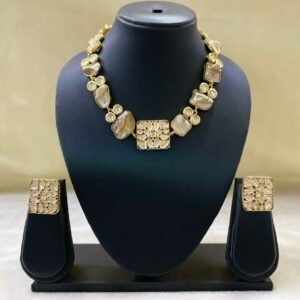 Elegant gold Kundan-style necklace set with matching square earrings displayed on black jewelry stand.
