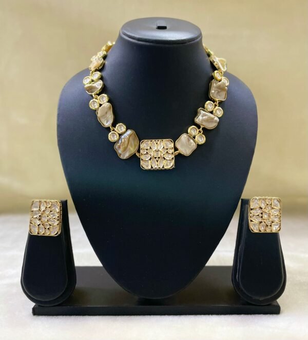 Elegant gold Kundan-style necklace set with matching square earrings displayed on black jewelry stand.